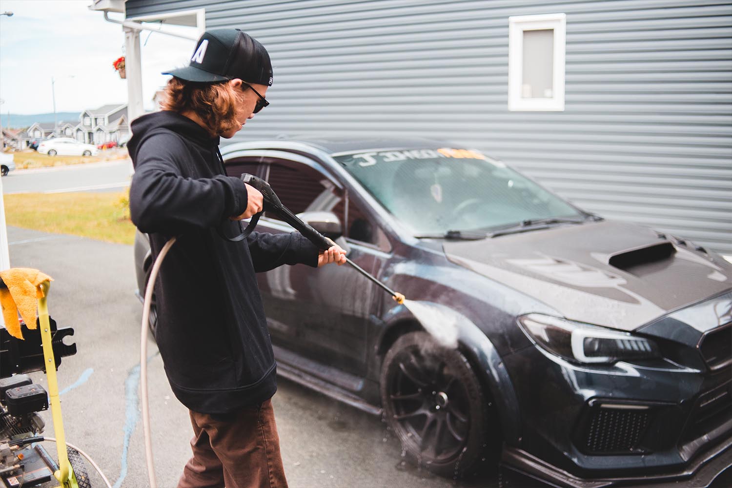 An image depicting a man washing a car as the American car wash industry blooms using water-efficient technology and eco-friendly cleaning products