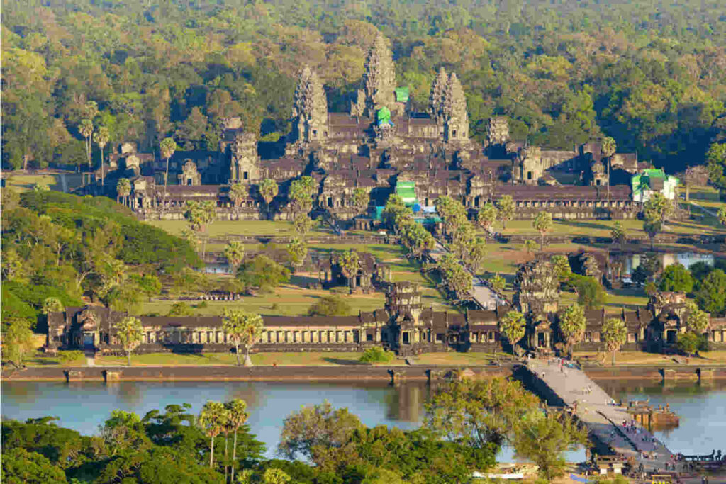 Aerial view of Angkor Wat temple complex with its iconic spires and intricate carvings, representing the world's largest religious monument and a symbol of ancient Khmer civilization.